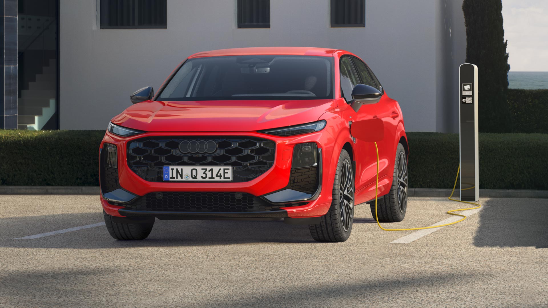 A red Q3 Sportback e-hybrid is parked in front of a charging station and is being charged with electricity.	