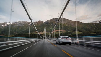 Ein Audi A6 Sportback e-tron in Gletscherweiß Metallic fährt über die Hardangerbrücke in Norwegen