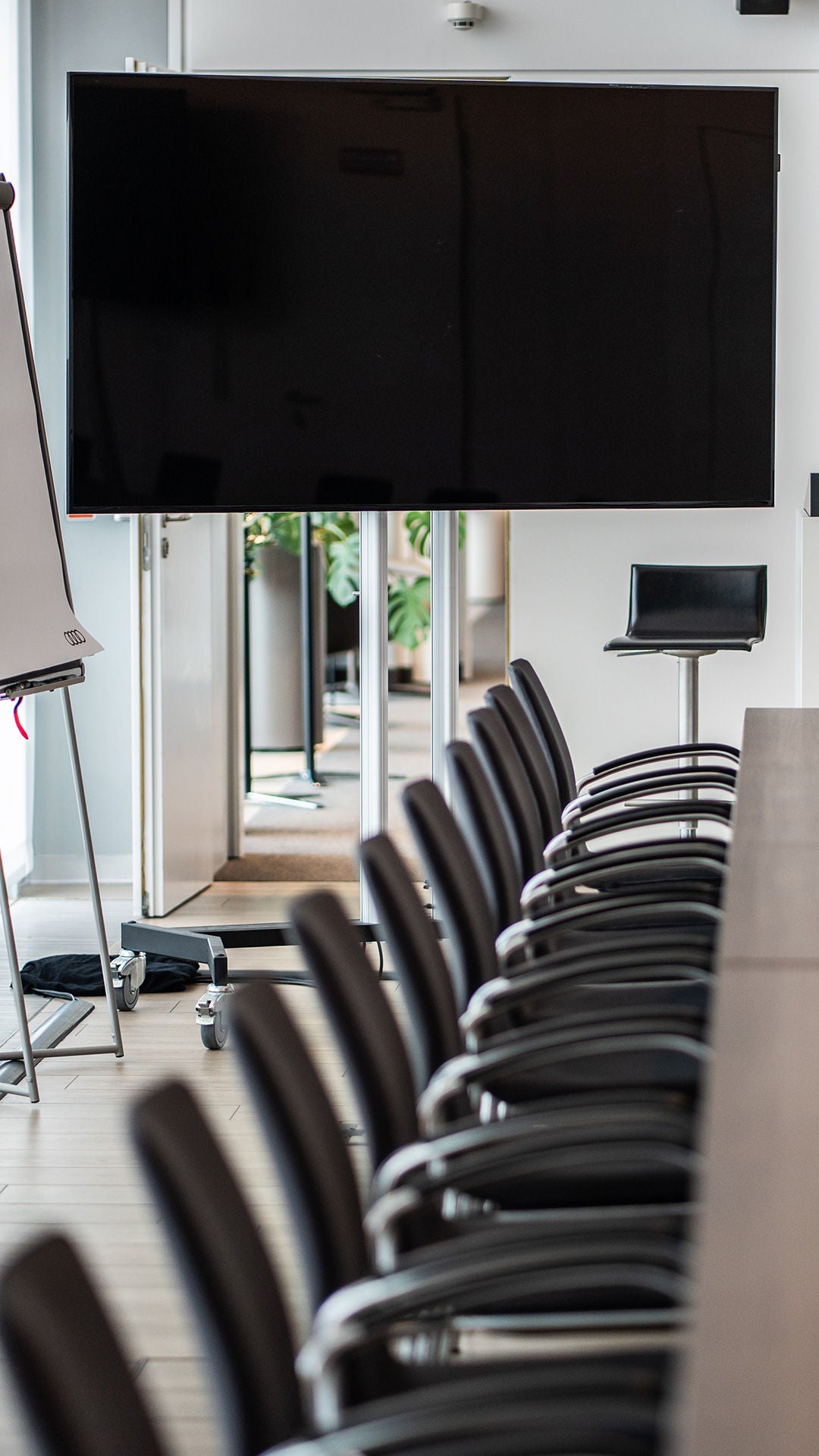 Konferenzraum mit einem langen Konferenztisch, Flipchart sowie einem großem Bild schirm und einem Rednerpult am Kopf des Tisches