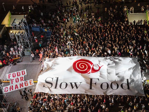 A crowd stands in front of a stage carrying a huge Slow Food banner.