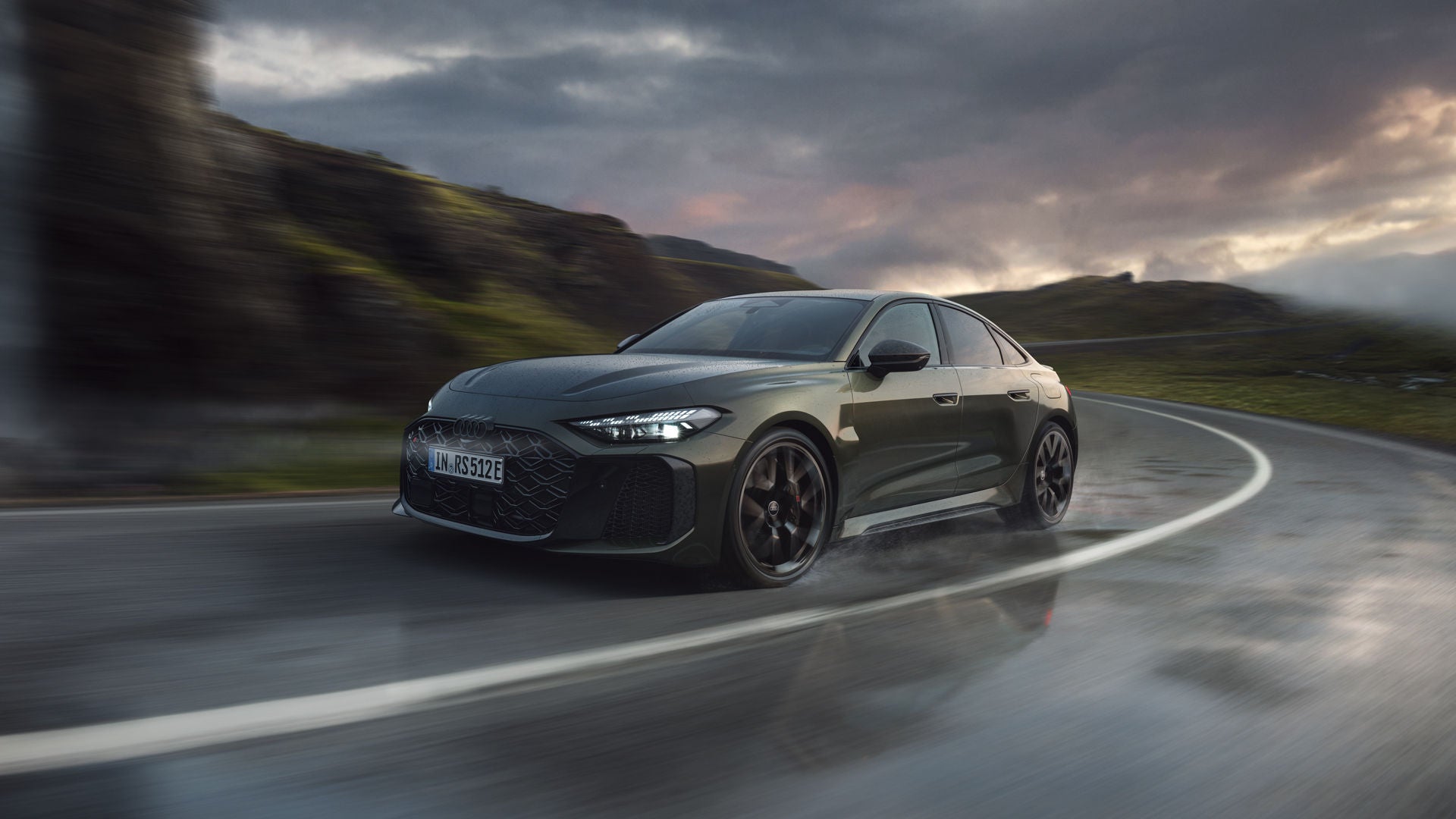 Die RS 5 Limousine schräg von vorn fährt eine Kurve auf einer Gebirgsstraße.