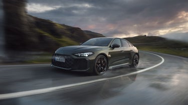 Die RS 5 Limousine schräg von vorn fährt eine Kurve auf einer Gebirgsstraße.