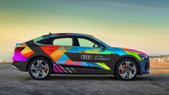 Eine bunt beklebtes Audi Modell mit dem Aufdruck "We live Diversity" neben dem Audi Logo.