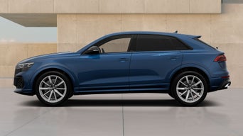 Blue Audi RS Q8 SUV performance parked by a modern beige wall, side view, featuring black windows and silver alloy wheels.