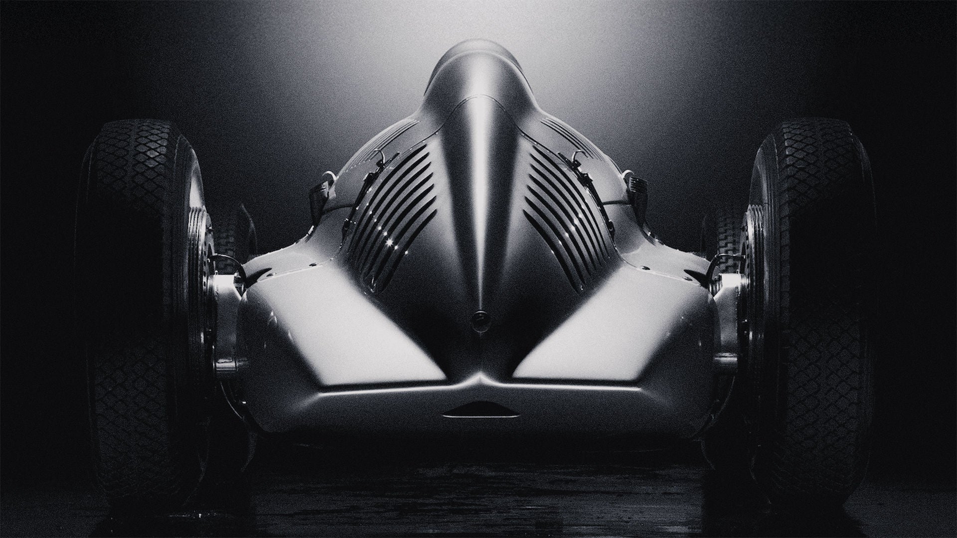 Rear view of a historic Audi racing car against a dark background.