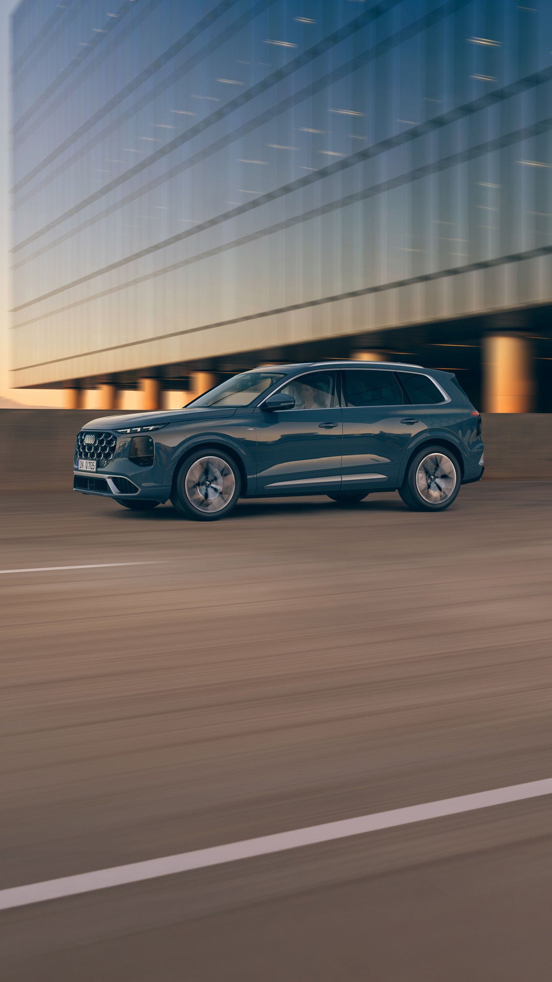 Q7 SUV kör på en väg i solnedgången.