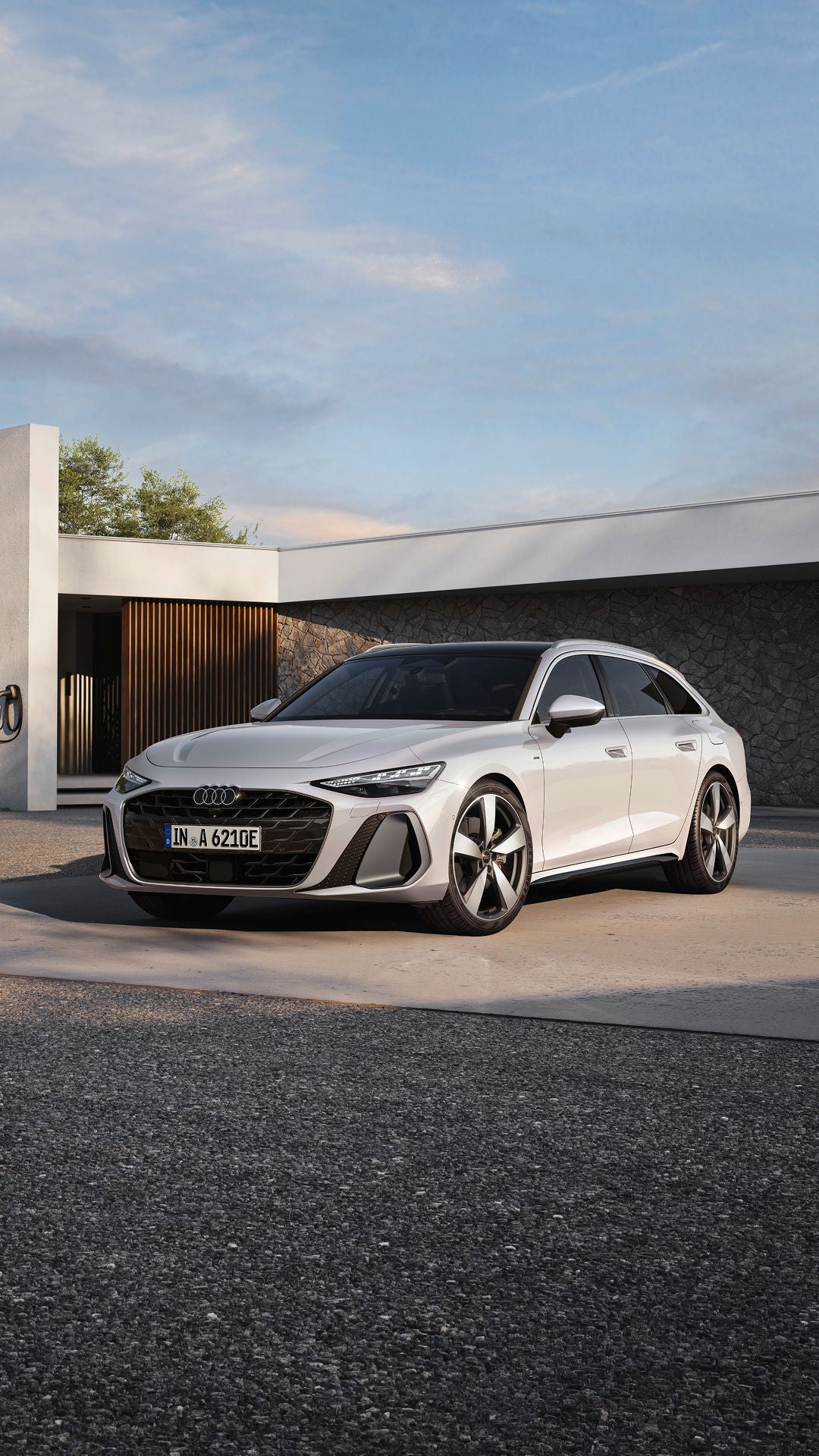 White Audi A6 Avant e-hybrid parked in front of a modern house