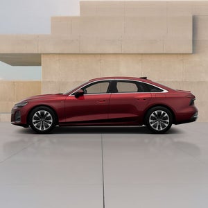 A red sedan features modern design elements, showcased against a minimalist concrete backdrop.