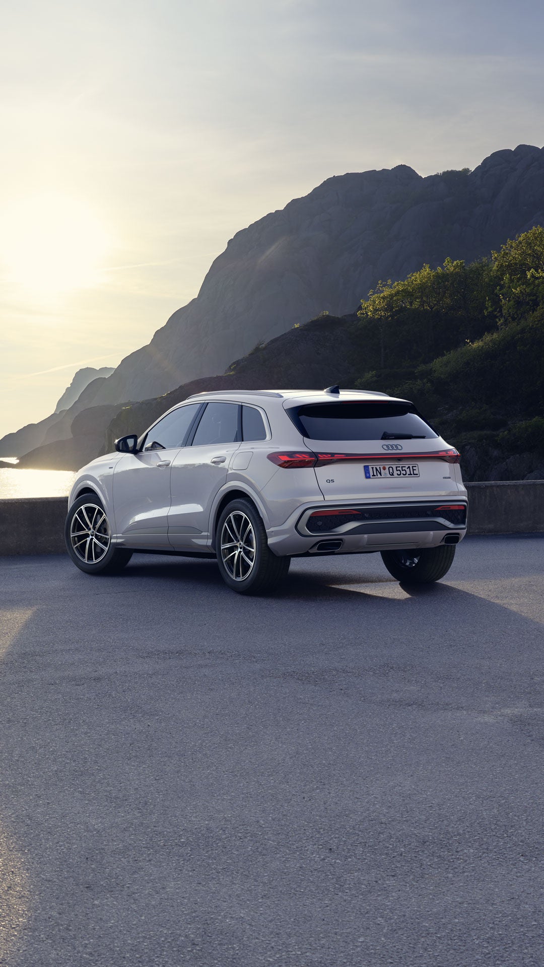 Ein weißer Q5 SUV e-hybrid steht auf einem Parkplatz an der Küste.