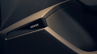 Nahaufnahme eines schwarzen Sonos-Lautsprechers im Fahrzeugtür-Panel mit strukturierter Oberfläche.