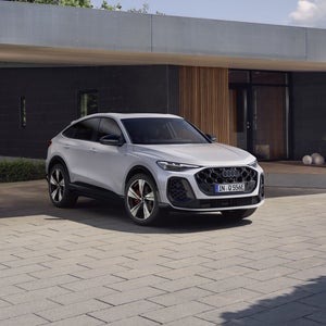 Die weiße Edition One des Q5 Sportback e-hybrid steht vor einem modernen Haus.