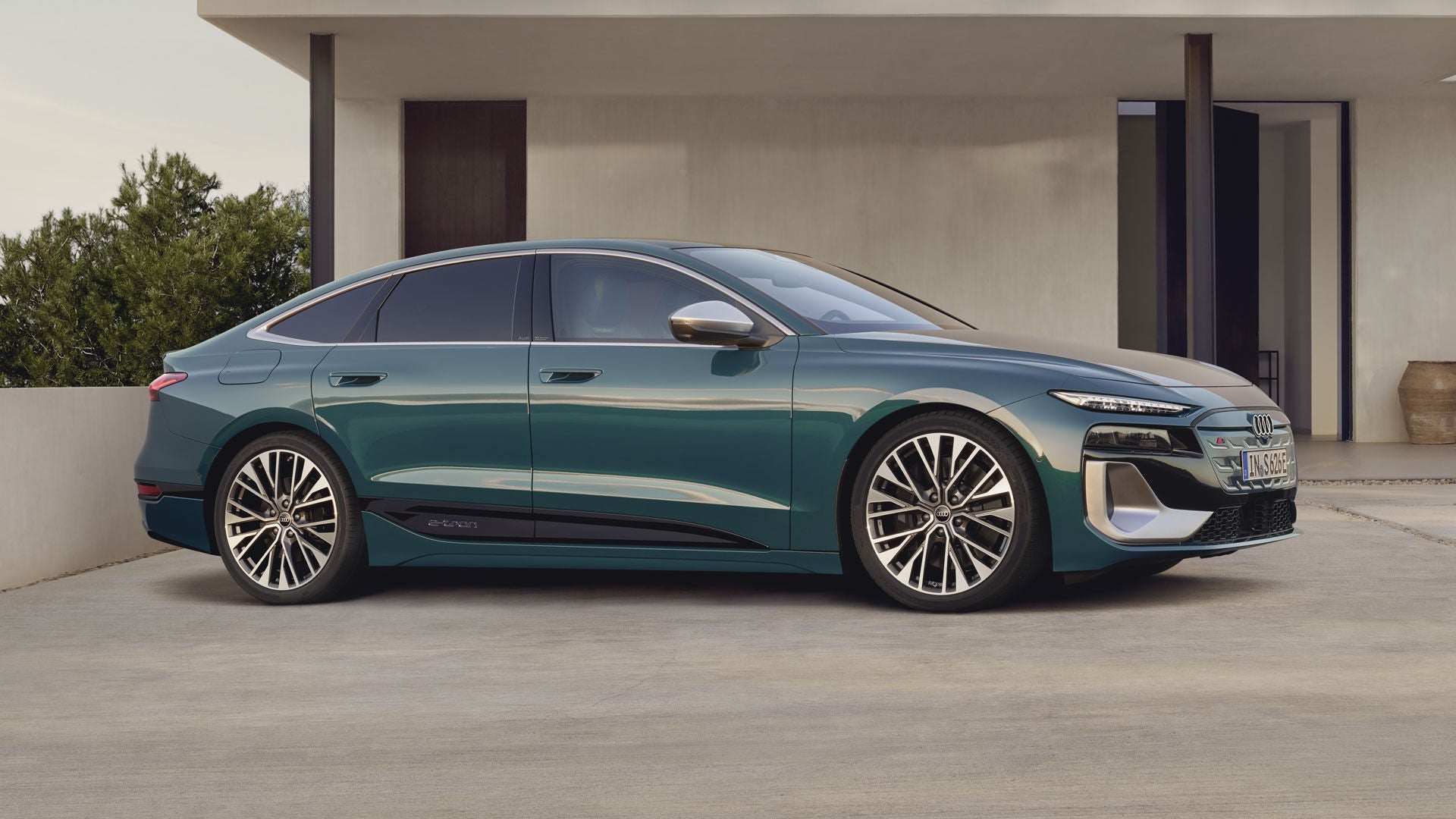 Der S6 Sportback e-tron steht im leicht schrägen Seitenprofil vor einem modernen Haus.