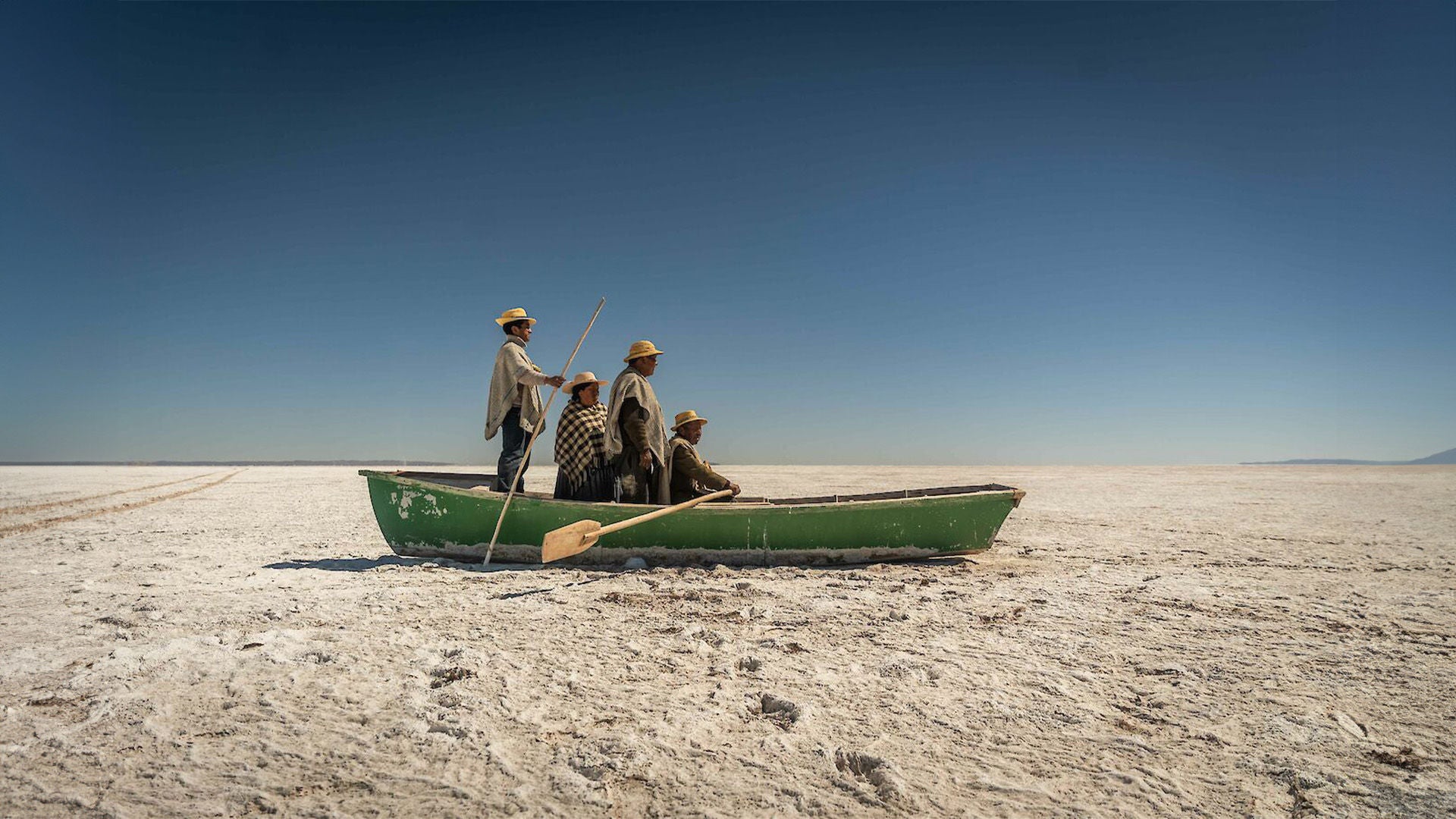 Vier Männer in einem Ruderboot inmitten einer Wüste