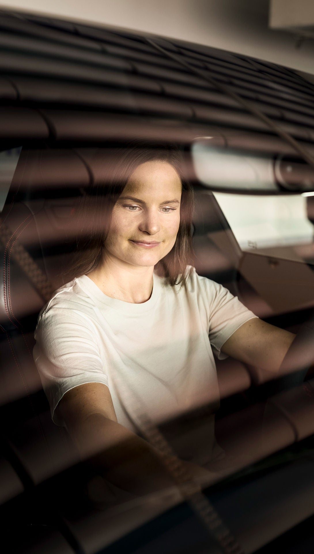 Melanie Schillinger is sitting in an Audi, looking down with one hand on the steering wheel