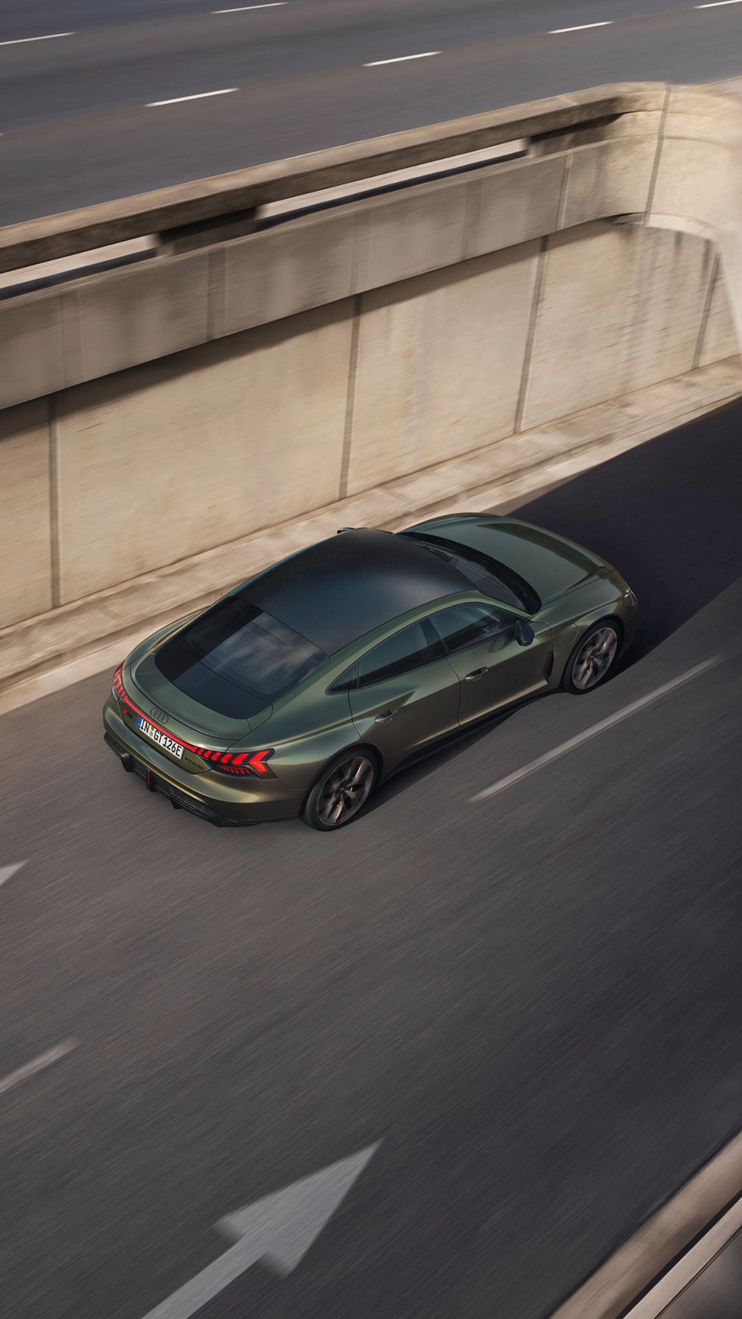 An aerial view of a green sports car navigating a concrete road, showcasing its stylish design and dynamic lines.