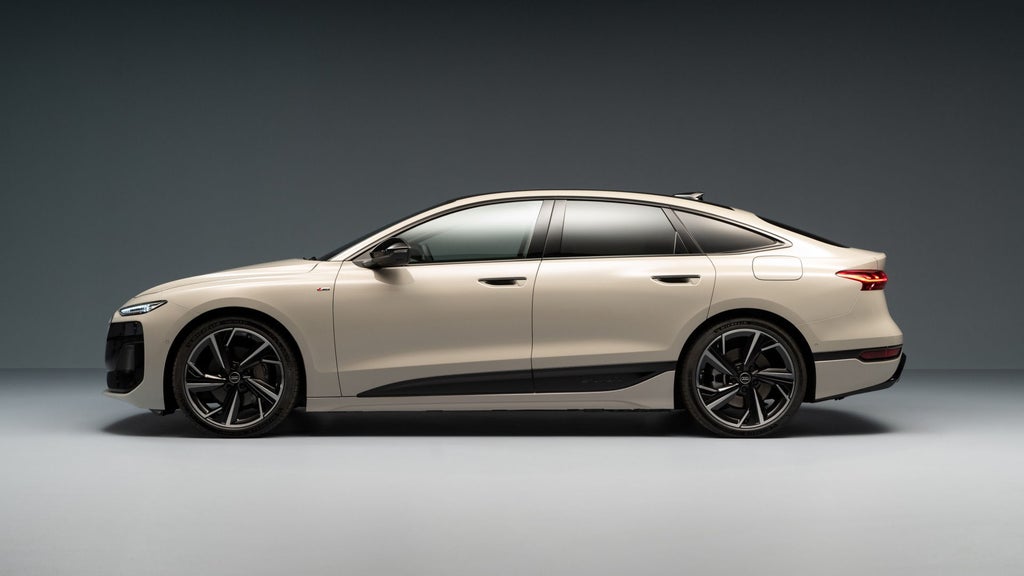 Zijaanzicht van de Audi A6 Sportback e-tron. De achterramen zijn donker. De auto staat voor een monochrome achtergrond. 