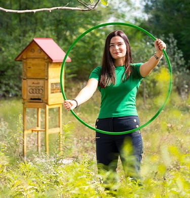 Woman with a green tire in front of an insect hotel