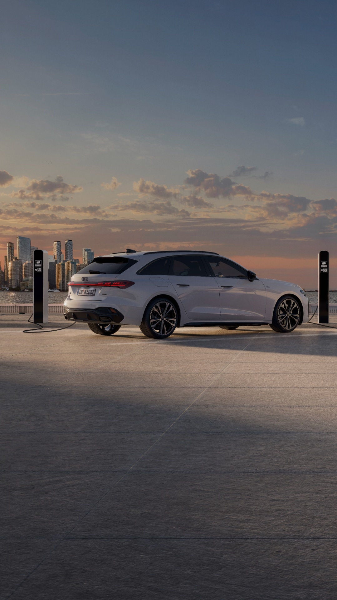 Parked Audi vehicle charging near waterfront outside modern cabin