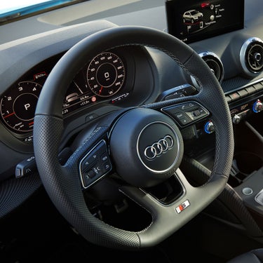 Interior view of a car with steering wheel, dashboard, and display screen.