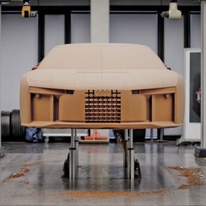 Een vooraanzicht van het houten model van de Audi Nuvolari op een hefplatform.