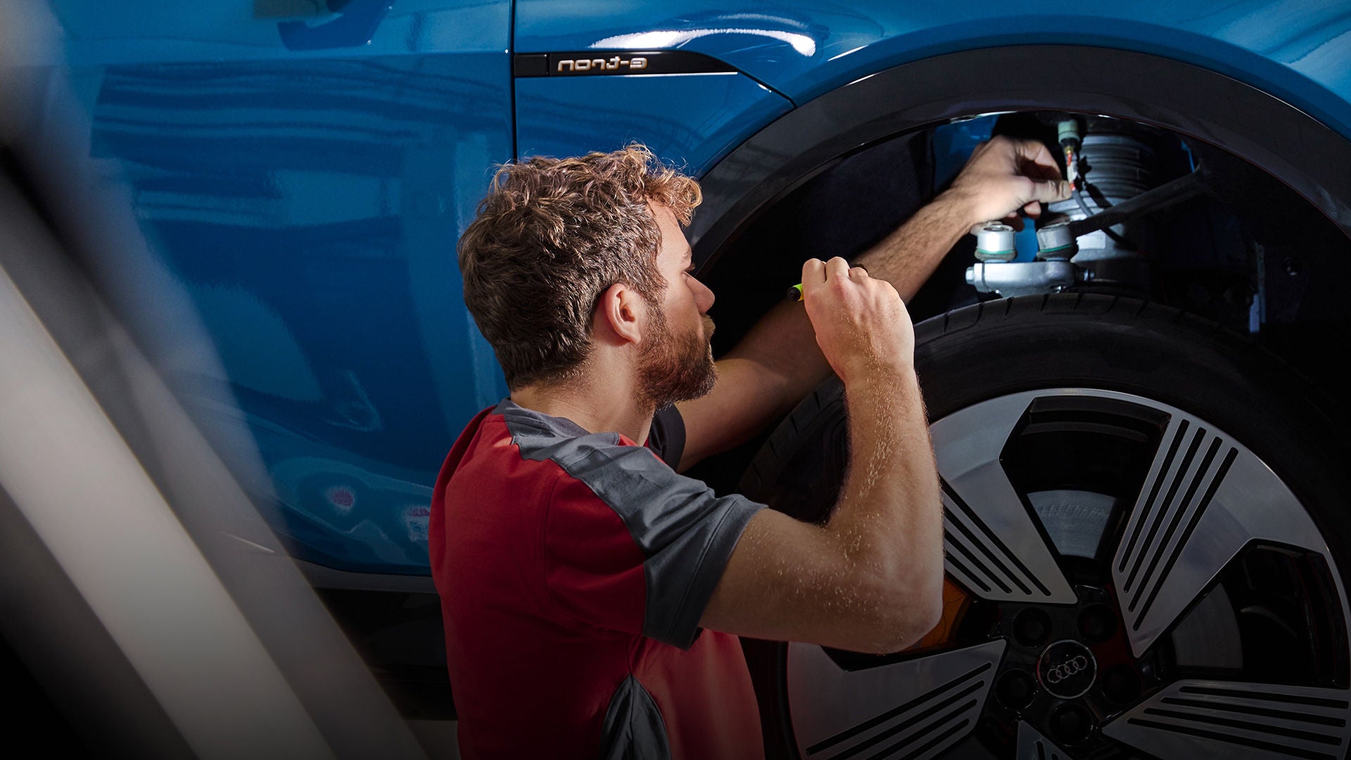 An Audi technician inspecting the inside of a wheel rim with a torch