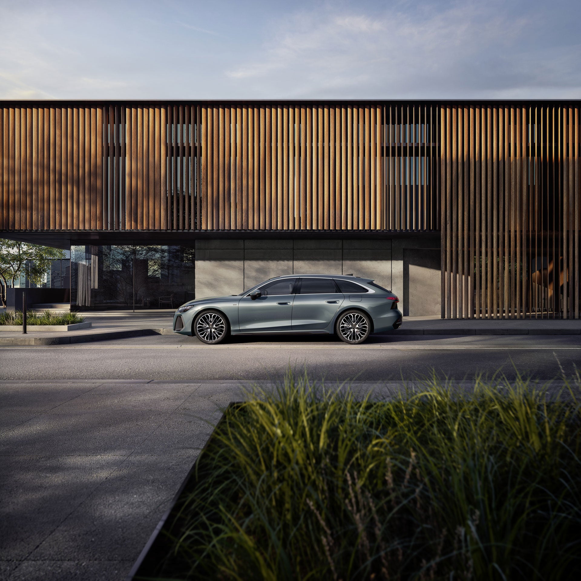 Ein Mann hält ein Smartphone mit geöffneter App neben einem grünen Audi SUV auf einem Parkplatz.