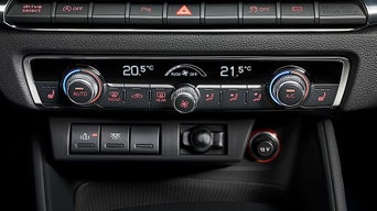 Nahaufnahme der Mittelkonsole eines Autos mit digitaler Zwei-Zonen-Klimaautomatik und diversen Bedienelementen.