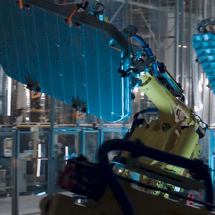 A man stands next to an Audi RS Q8 and gazes into the distance. A skyline can be seen on the horizon.