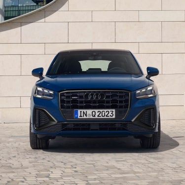 A blue Audi SUV parked in front of a beige tiled wall.