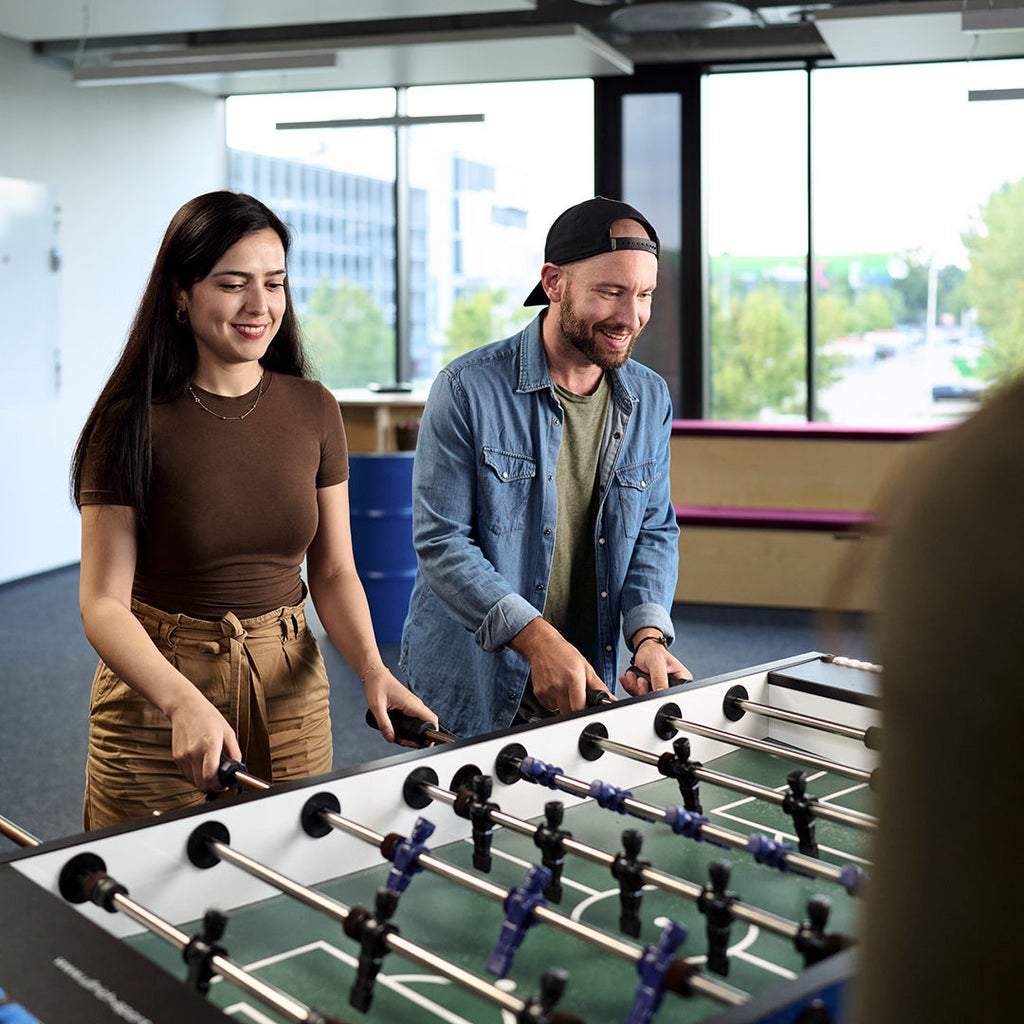 Sebastian Kister spielt Tischkicker mit seinen Kollegen.