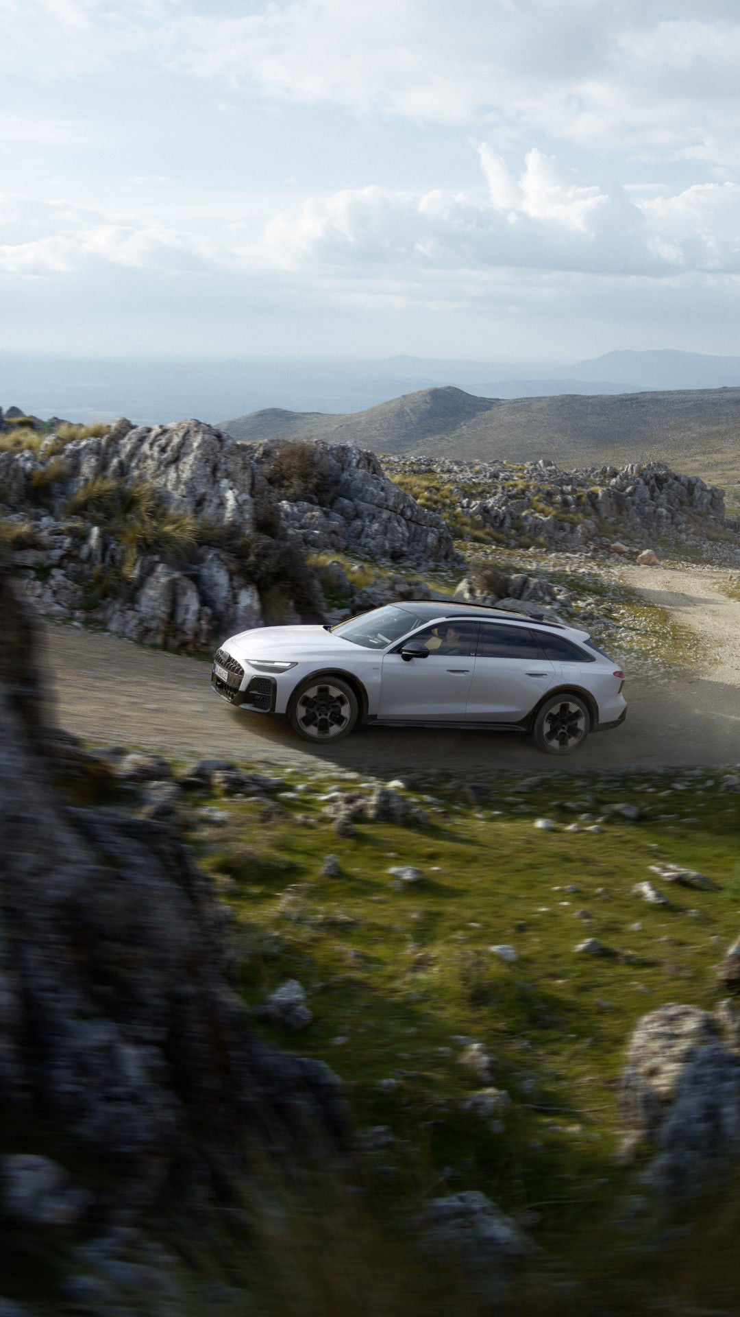 De A6 allroad e-hybrid quattro op een onverharde weg in de bergen.
