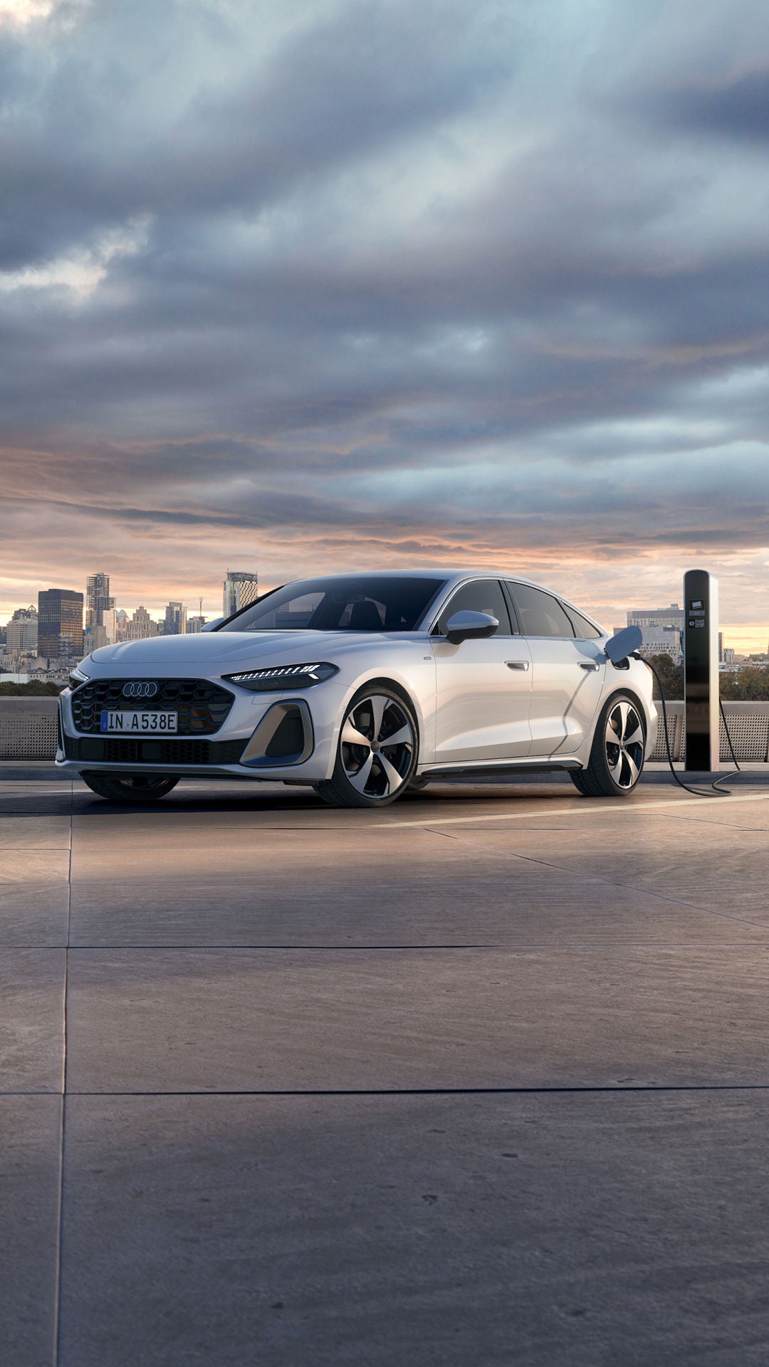White Audi electric vehicle plugged on an EV charger with a city background