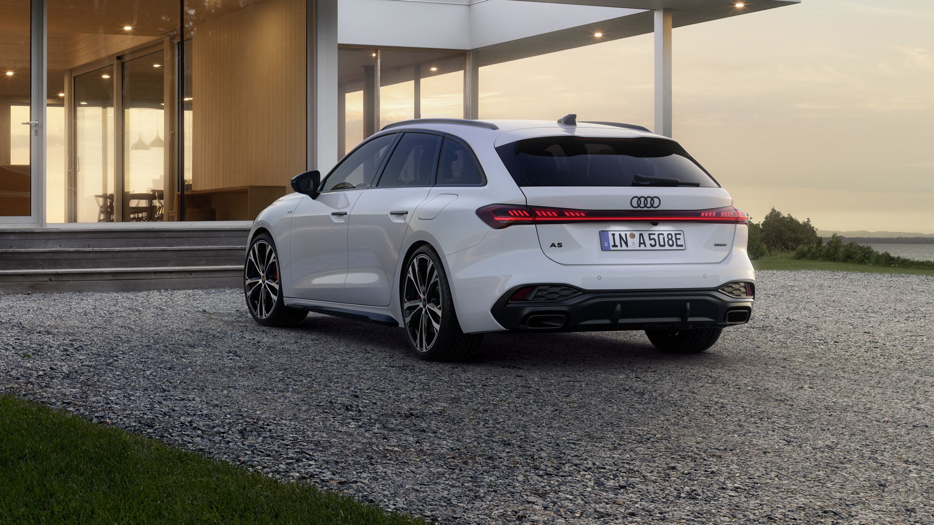 A5 Avant e-hybrid gezien van schuin linksachter, staat geparkeerd voor een modern huis.