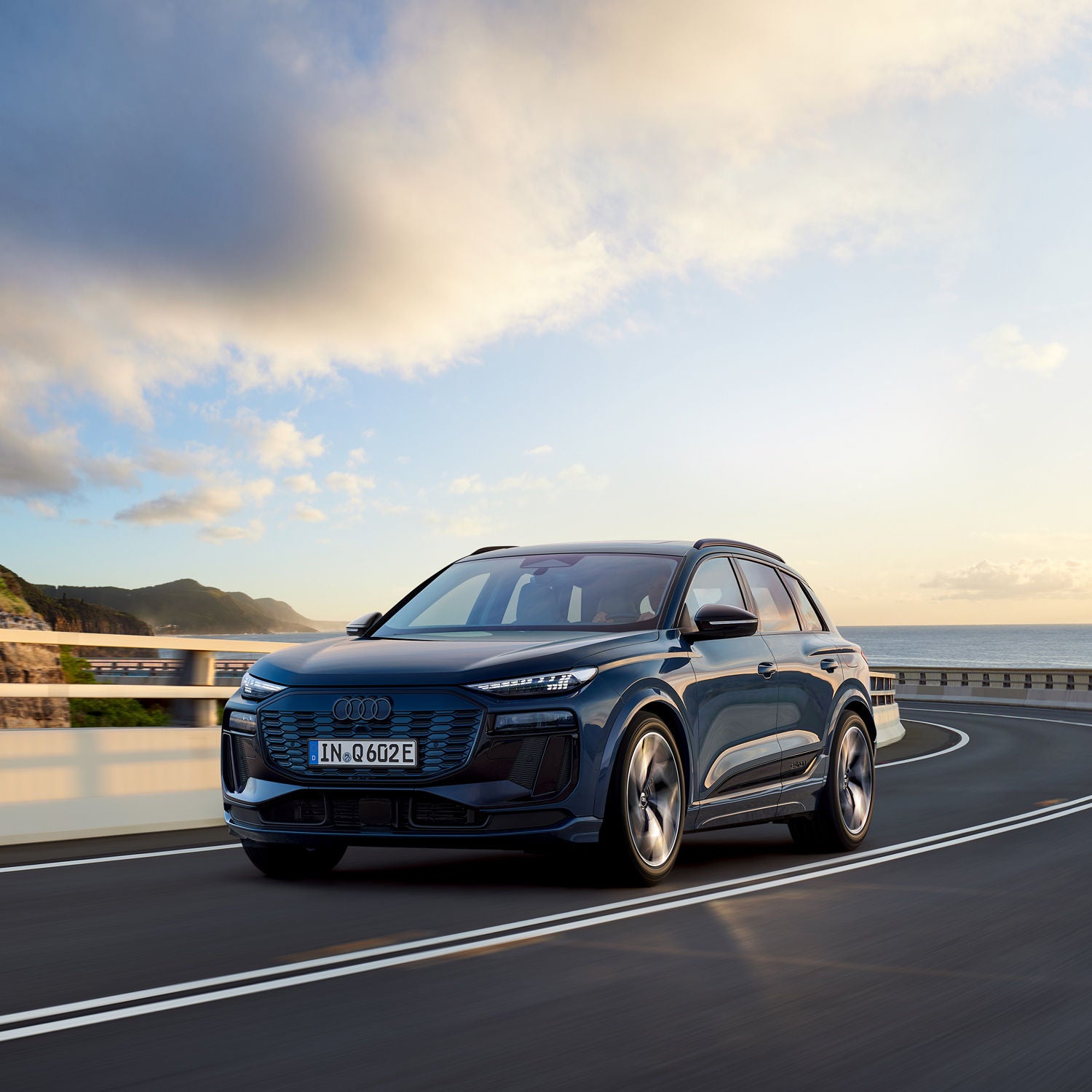 An Audi vehicle driving on a road, the road behind curving towards the left behind the vehicle