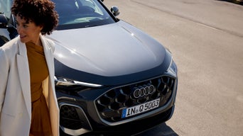 Frau steht vor einem dunkel blauen Audi 