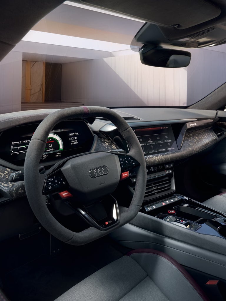 Cockpit des Audi RS e-tron GT performance mit Lenkrad, digitalen Anzeigen und Mittelkonsole mit Schaltwippen und Bedienfeldern.