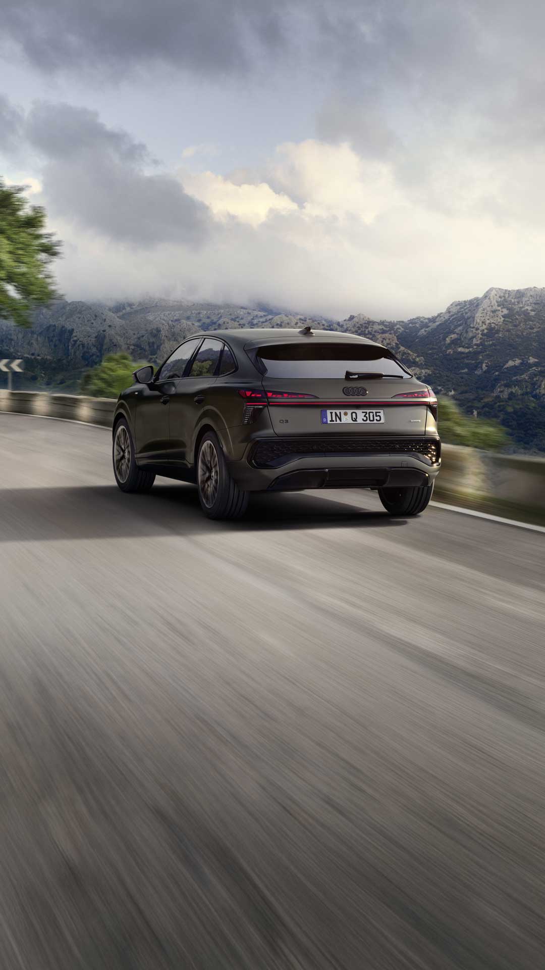 The Q3 Sportback is parked on a paved path in front of the window front of a building.