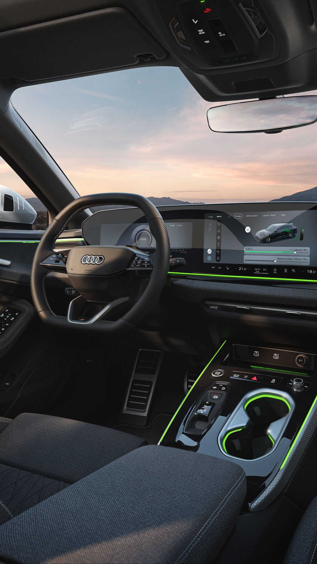 Blick auf die Displays und das Lenkrad im Cockpit des A6 Avant e-hybrid. Durch die Windschutzscheibe sind Berge zu sehen.