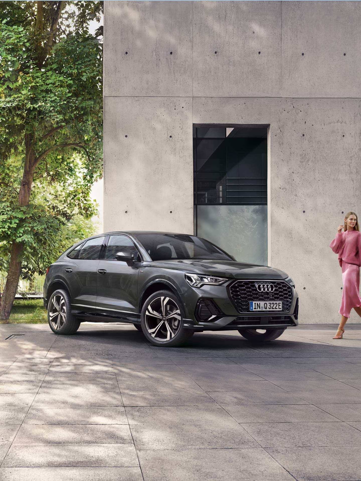 Lady in pink outfit approaching Audi Q3 Sportback TFSI e outside house.