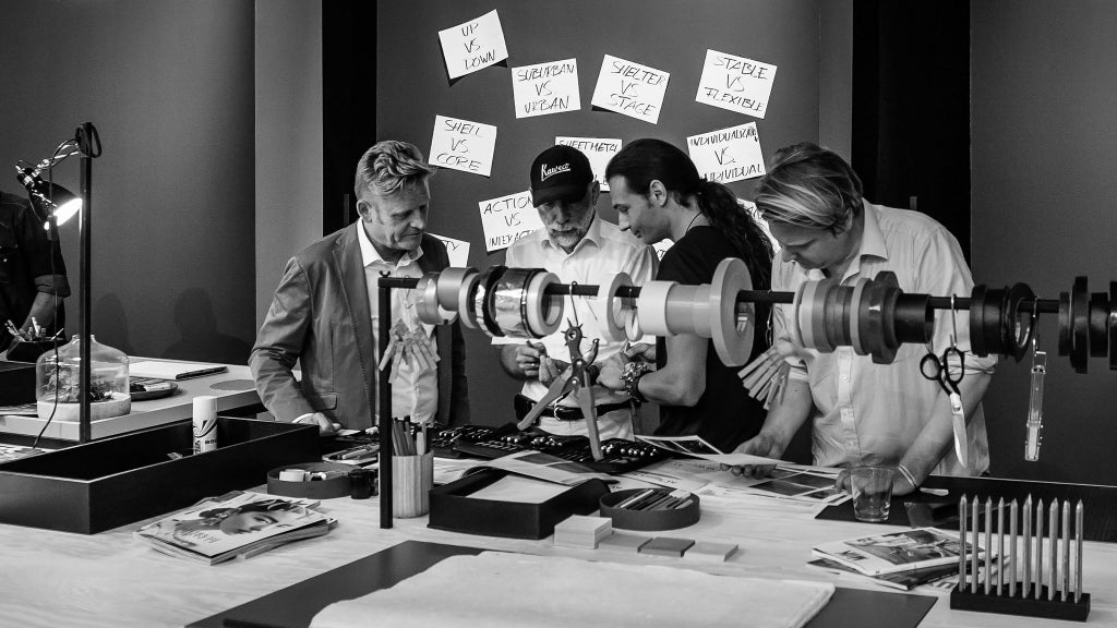 Svartvit bild på fyra män som diskuterar design.