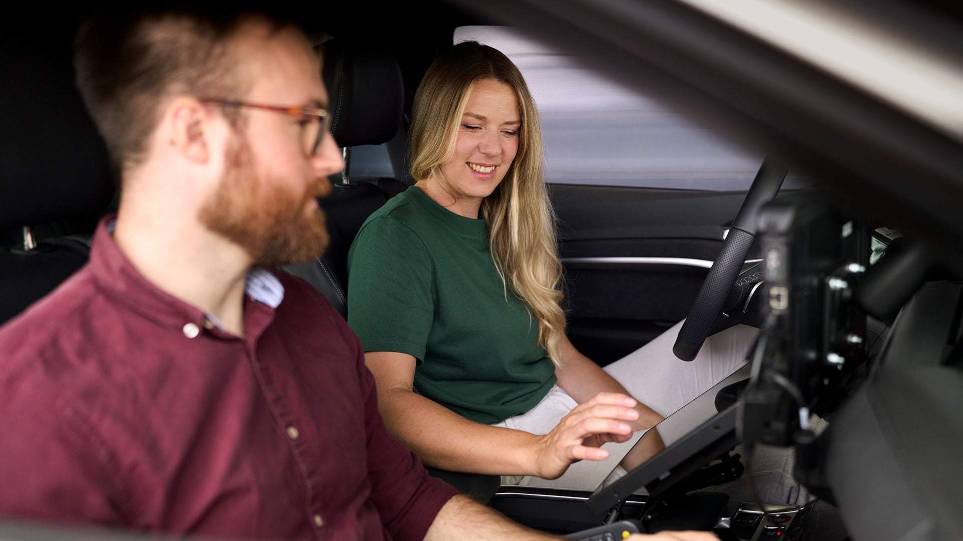 Lissi Lanz sitzt in einem Audi und zeigt ihrem Kollegen etwas auf einem Tablet