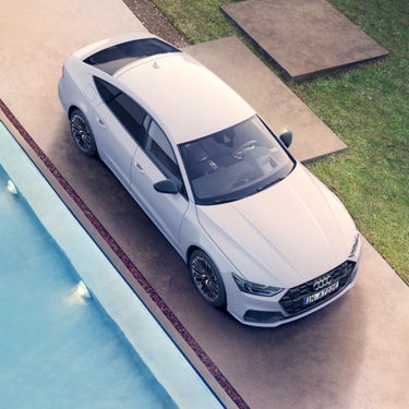 White Audi parked beside a pool, top aerial view.