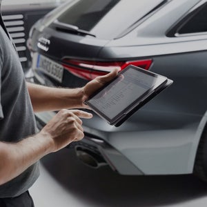 A hand holding a table next to a car
