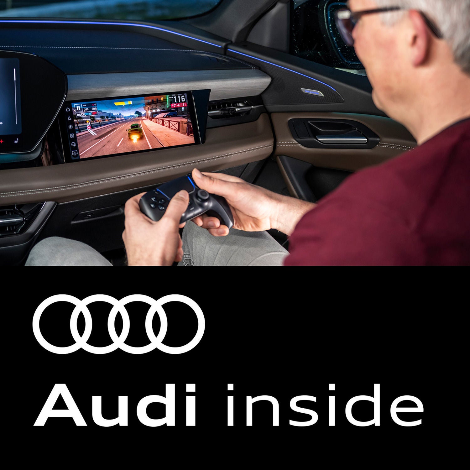 Ein Mann auf dem Beifahrersitz hält ein Gamepad und spielt ein Rennspiel auf dem MMI eines Audi. Darunter steht "Audi inside"