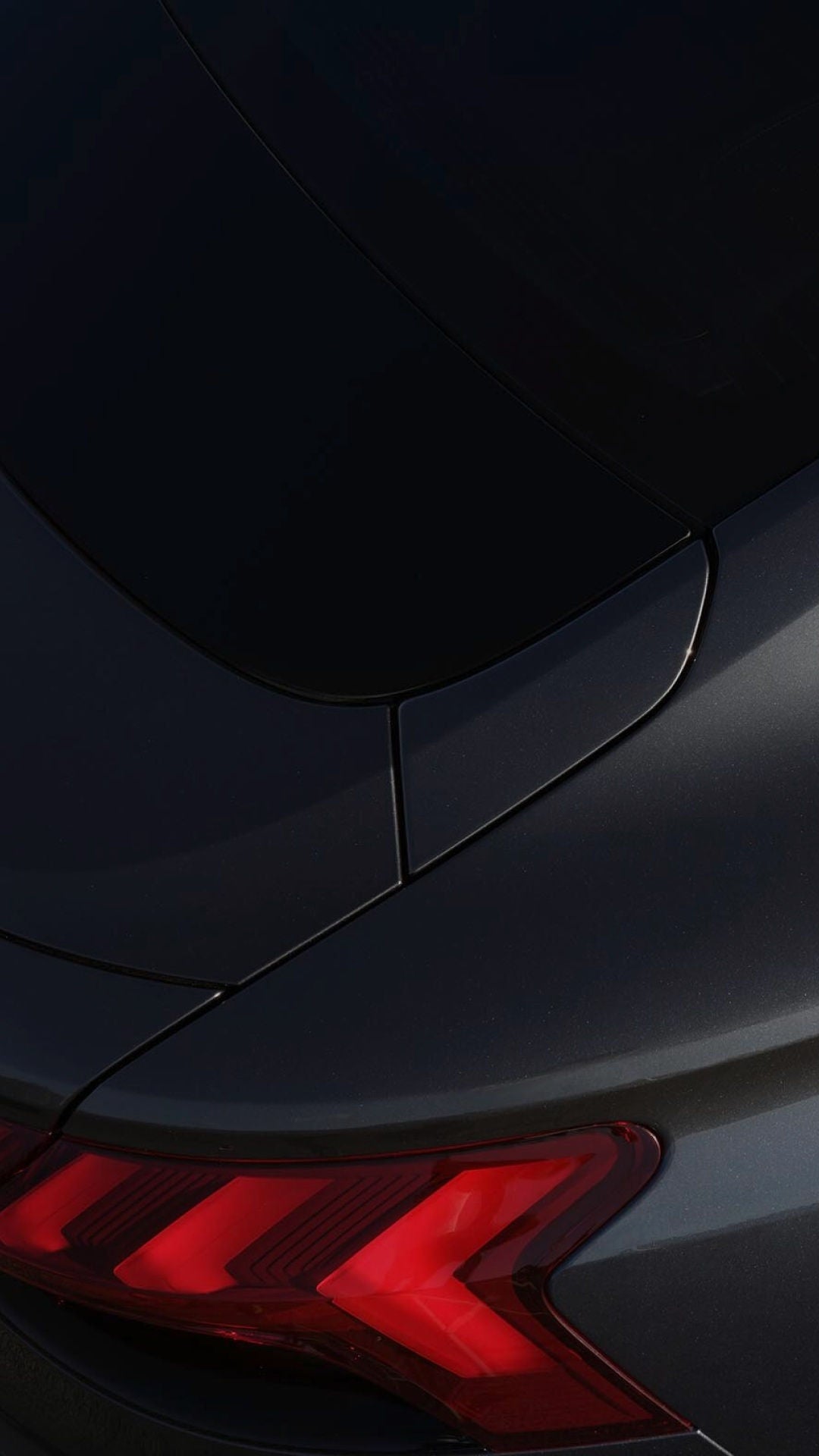 Close-up of a grey Audi car, highlighting smooth curves, a glossy finish, illuminated taillights, and a sophisticated design.