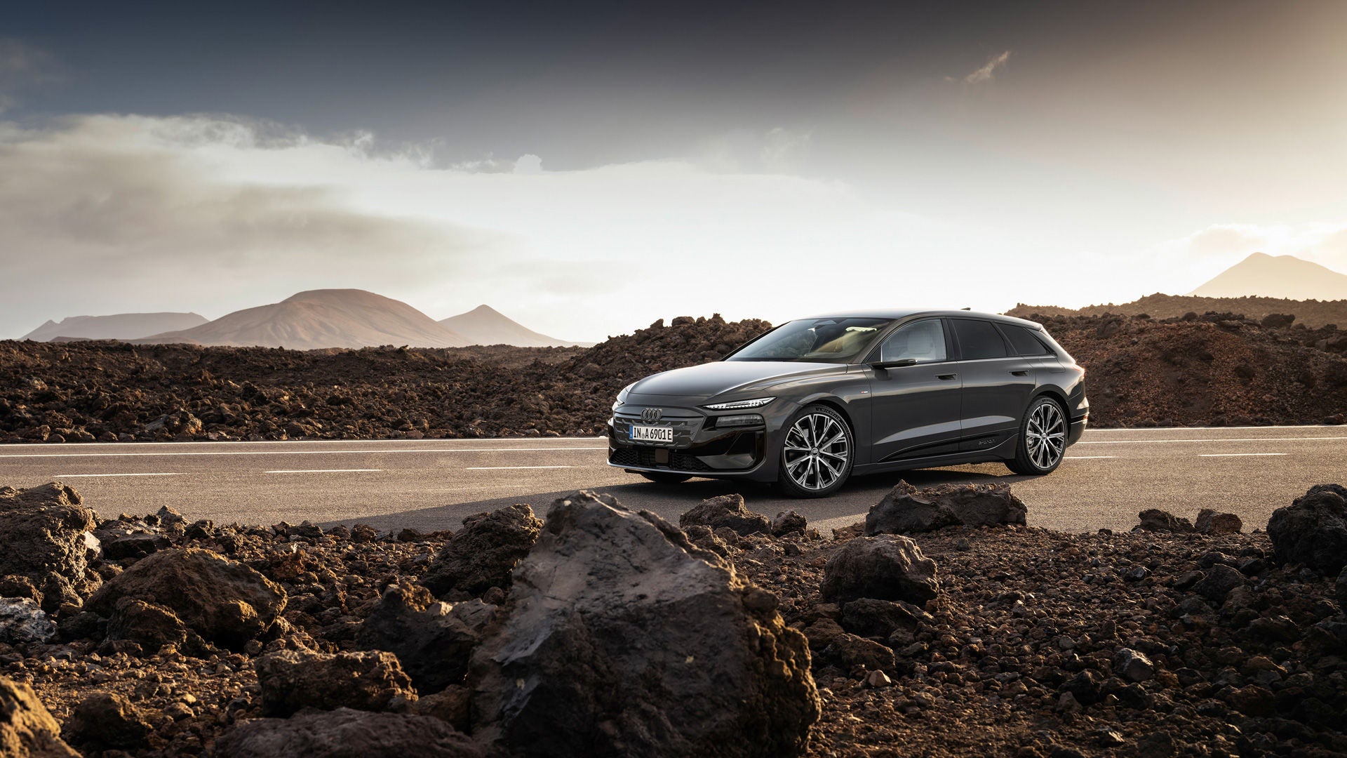 Der Audi A6 Avant e-tron performance steht auf einer Straße vor einer Bergkulisse. Neben der Straße liegen Steine und Geröll.