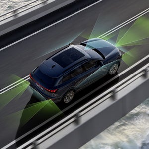 Q6 SUV e-tron sedd uppifrån. Från bak- och framsidan delar gröna och blå vektorer upp områdena bakom och framför fordonet.