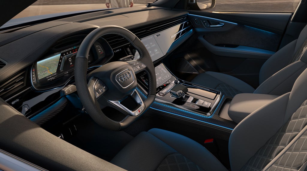 Blick in das Cockpit des SQ8 SUV von der Fahrerseite mit Fokus auf das Lenkrad, die digitalen Displays und die Sportsitze.
