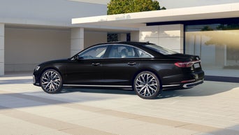 Der A8 steht im schrägen Seitenprofil vor einem futuristischen Haus.