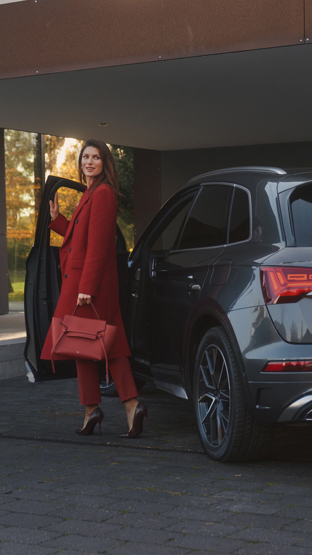 Woman posing by the door of a dark grey Audi Q5 vehicle